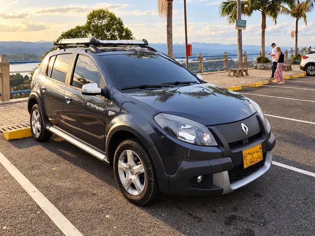 Renault Sandero gris oscuro de Latidos Tours estacionado en un mirador con palmeras, al atardecer