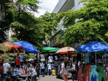 Calle comercial con toldos y vendedores en el centro de Medellín, El Hueco
